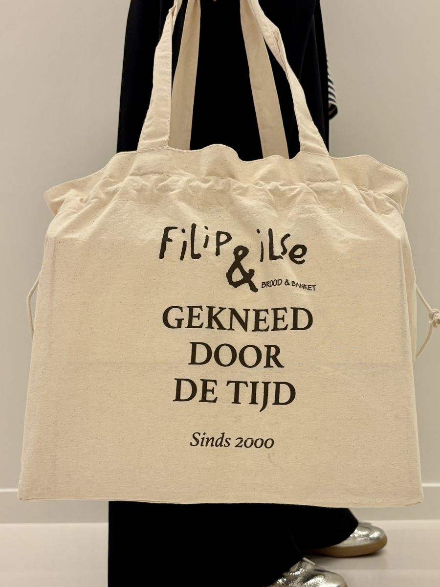 Een stoffen draagtas van Filip & Ilse met de tekst Gekneed door de tijd, sinds 2000
