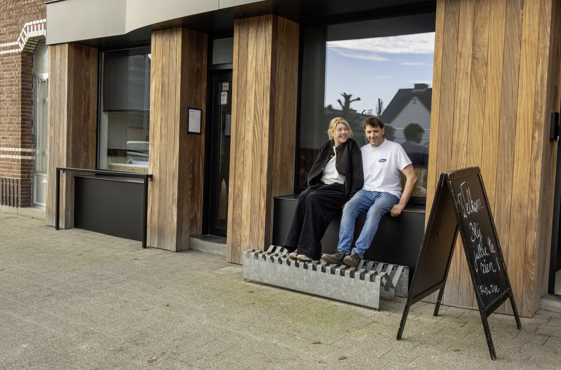 Filip en Ilse zitten samen op de vensterbank voor hun bakkerij